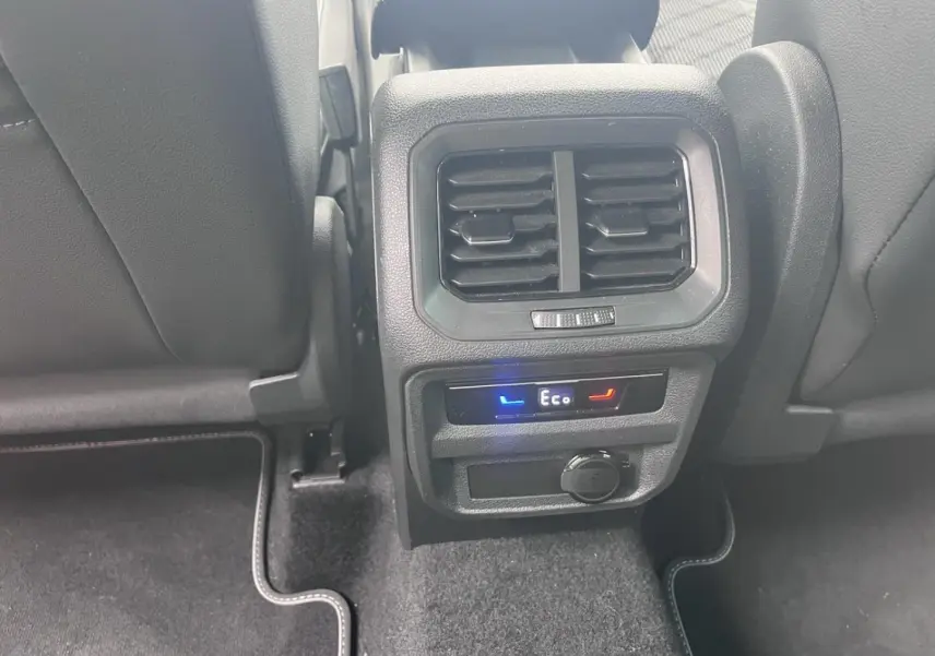 Vue rapprochée de la console arrière du Volkswagen Tiguan gris Dauphin avec commandes climatisation et prise 12V.