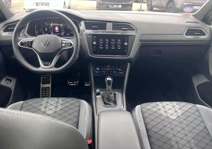Vue intérieure avant du Volkswagen Tiguan gris Dauphin, avec volant multifonction, écran tactile central et sièges sport gris.