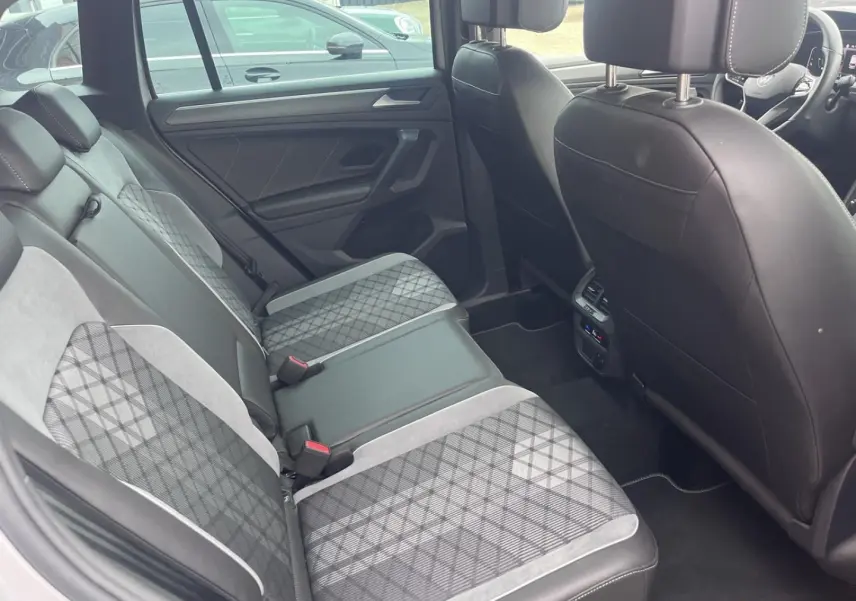 Vue intérieure arrière du Volkswagen Tiguan 1.4 eHybrid 2023, sièges arrière en tissu et cuir noir avec motifs géométriques.