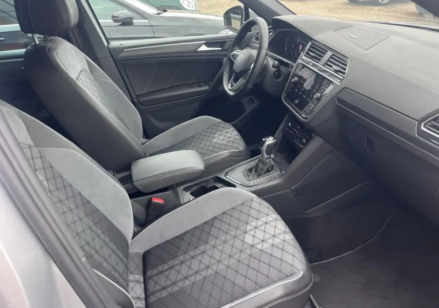 Vue intérieure côté conducteur du Volkswagen Tiguan 1.4 eHybrid 2023 avec sièges sport gris et tableau de bord moderne.