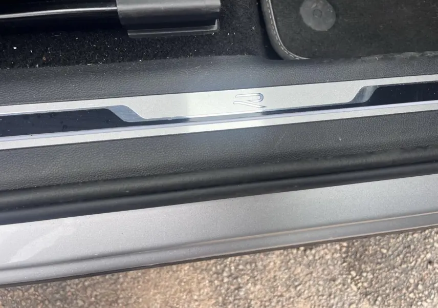 Gros plan sur la plaque de seuil de porte avec logo R du Volkswagen Tiguan gris dauphin métallisé.