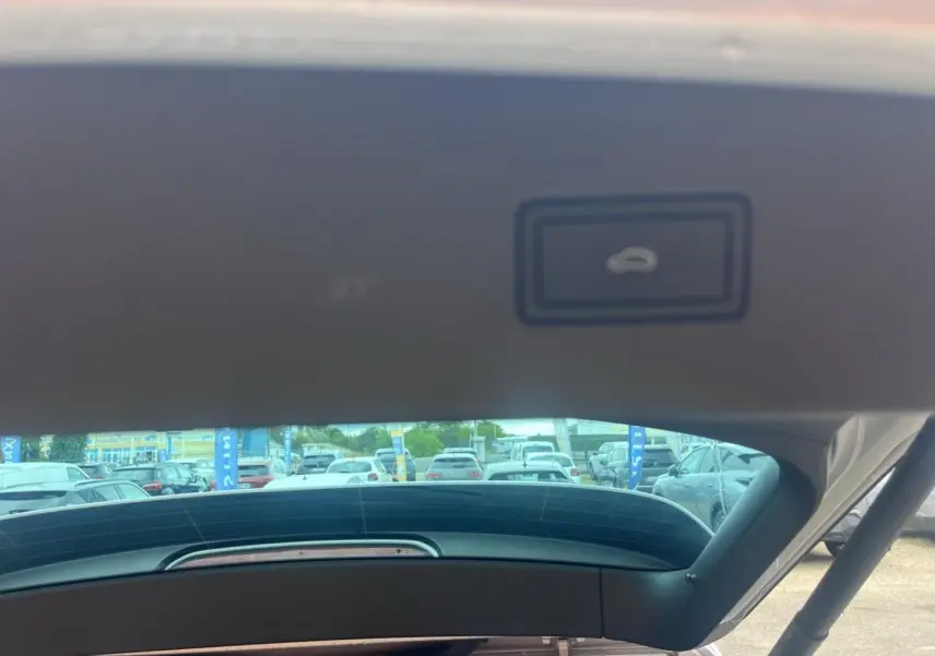 Vue intérieure du hayon ouvert du Volkswagen Tiguan gris dauphin métallisé, montrant la commande d'ouverture du coffre.