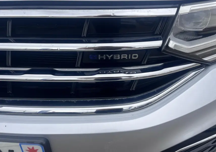 Gros plan sur la calandre avant gris dauphin métallisée du Volkswagen Tiguan 1.4 eHybrid avec badge eHybrid visible.