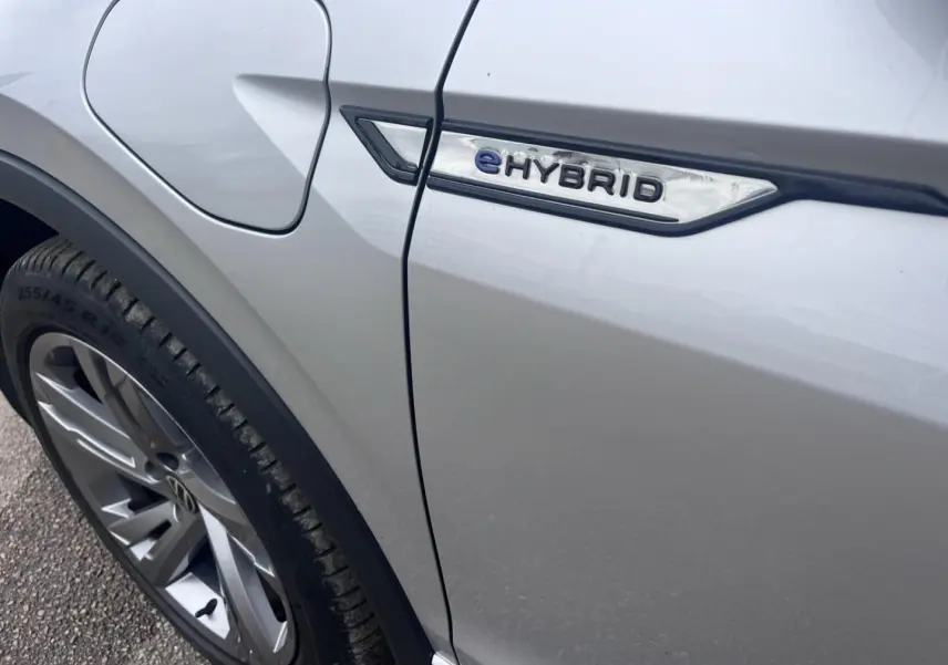 Gros plan sur le côté gauche gris dauphin métallisé du Volkswagen Tiguan 1.4 eHybrid avec logo eHybrid près de la trappe à carburant.