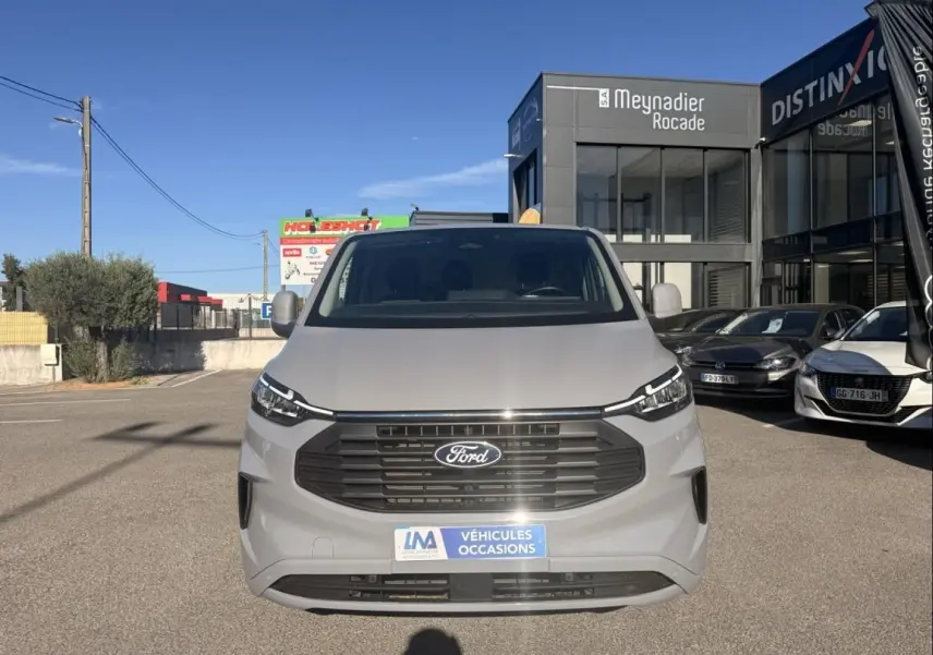 Vue frontale d'un Ford Transit Custom Fourgon gris 2024 avec calandre noire et plaque "Véhicules Occasions".