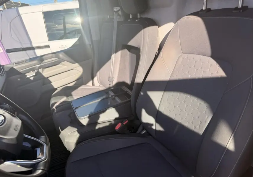 Vue intérieure côté conducteur du Ford Transit Custom Fourgon gris 2024, montrant les sièges avant et le volant.
