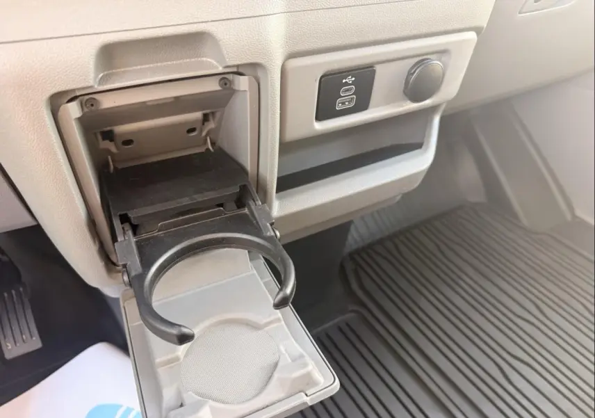 Détail intérieur du Ford Transit Custom 2024 montrant un porte-gobelet déplié et une prise USB sur fond gris.