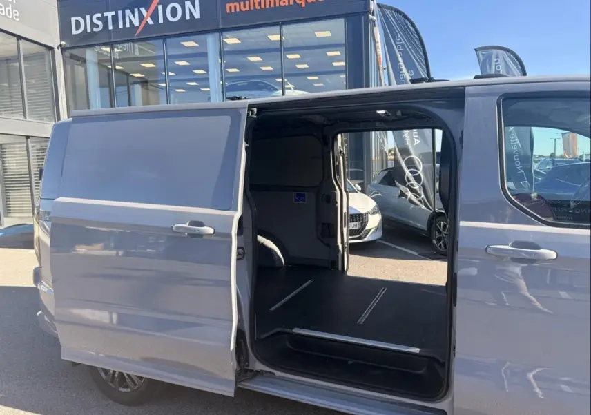Vue latérale droite d’un Ford Transit Custom gris 2024 avec porte coulissante ouverte montrant l’espace de chargement vide.