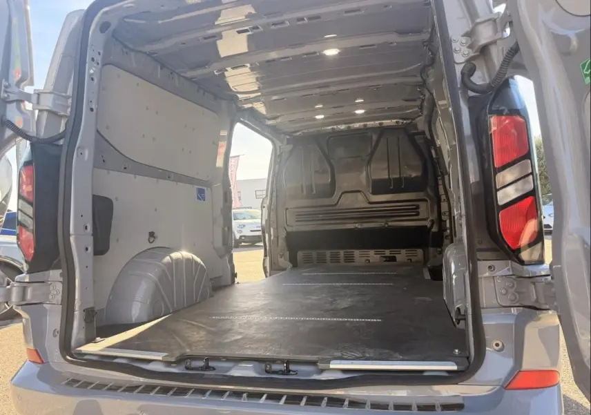 Vue arrière ouverte du Ford Transit Custom Fourgon gris 2024, montrant l’espace de chargement vide et le plancher plat.