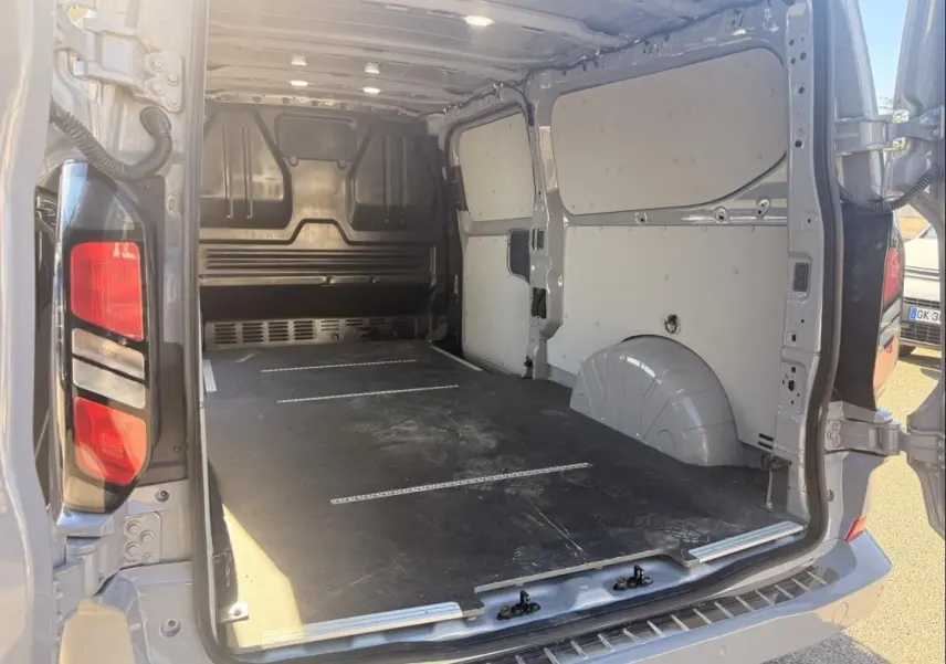 Vue arrière ouverte du Ford Transit Custom Fourgon gris 2024, montrant l’espace de chargement vide et les portes battantes.