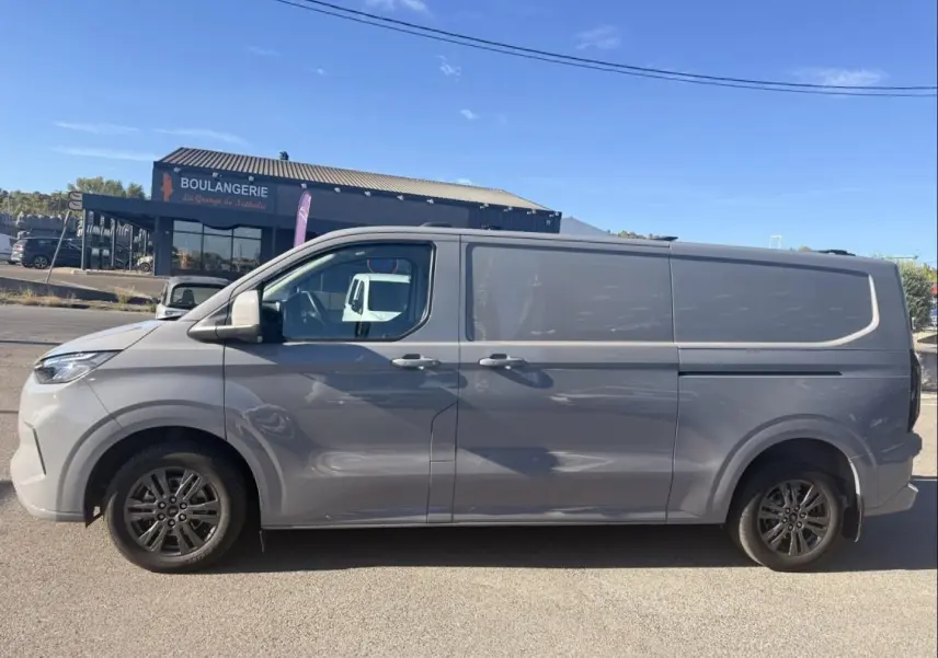 Vue latérale gauche d’un Ford Transit Custom Fourgon gris 2024 avec jantes alliage et carrosserie lisse.