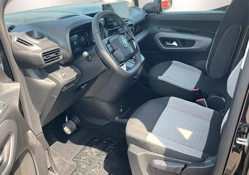 Vue intérieure côté conducteur du Citroën Berlingo noir 2026, montrant le tableau de bord et les sièges bicolores gris et noir.