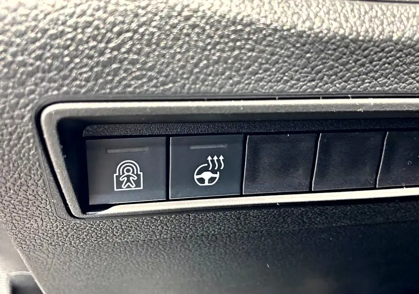 Gros plan sur les boutons de commande du tableau de bord noir du Citroën Berlingo N1 2026, dont le volant chauffant.