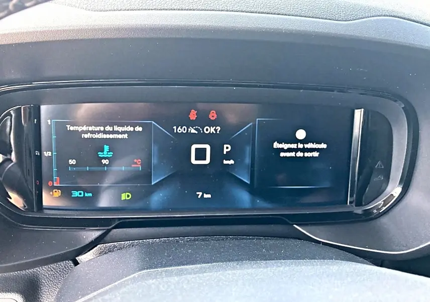 Vue rapprochée du tableau de bord numérique du Citroën Berlingo noir, affichant les informations de conduite et alertes.