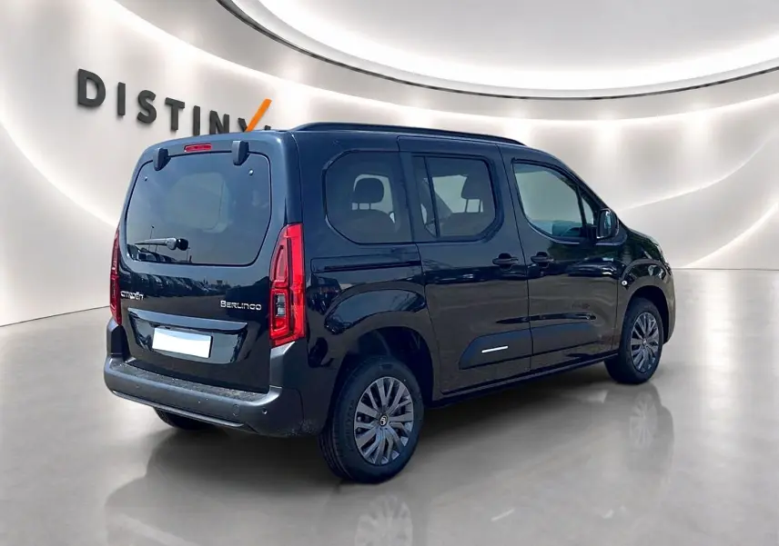 Vue 3/4 arrière droite d'un Citroën Berlingo noir avec portes latérales et jantes alu dans un showroom lumineux.