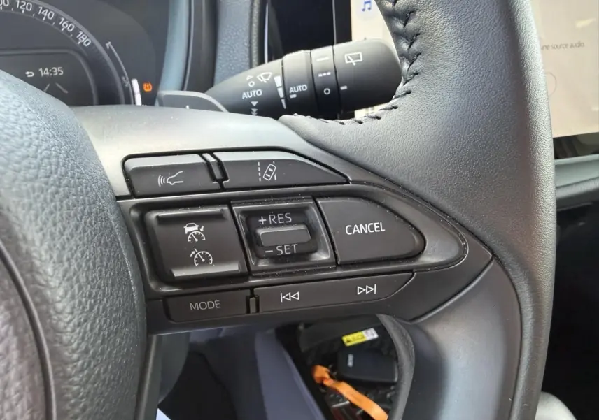 Gros plan sur les commandes au volant de la Toyota Aygo X 2025, montrant les boutons de régulateur et d'assistance.