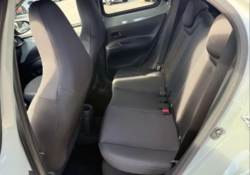 Vue intérieure côté droit sur les sièges arrière noirs de la Toyota Aygo X 2025, avec porte ouverte et tissu uni.