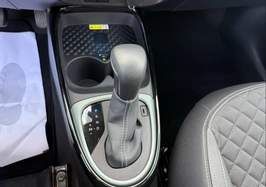Gros plan sur le levier de vitesse automatique de la Toyota Aygo X 2025, intérieur noir avec surpiqûres blanches.