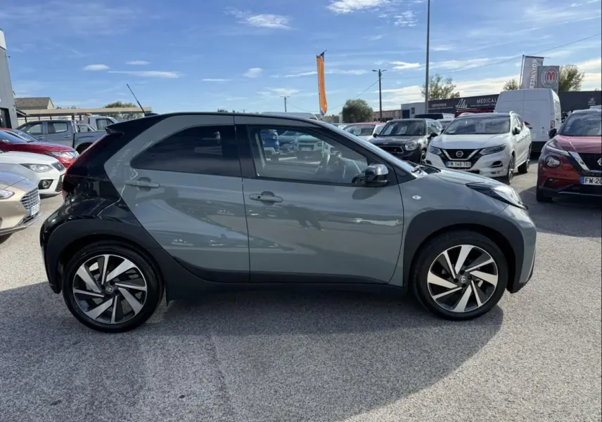 Vue de profil côté gauche d'une Toyota Aygo X 2025 vert aventurine avec toit noir et jantes distinctives en alliage.