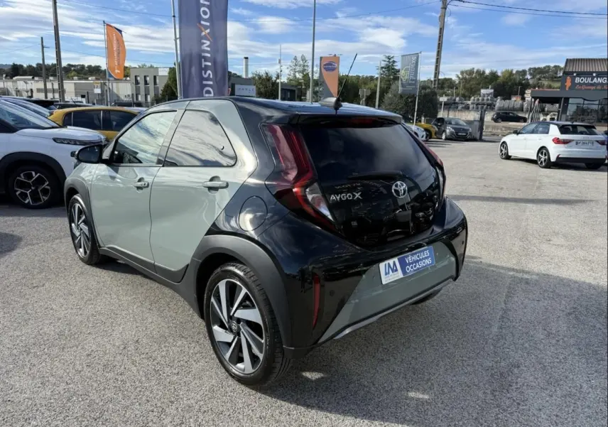 Vue 3/4 arrière droite d'une Toyota Aygo X 2025 vert aventurine avec toit noir et feux arrière distinctifs en forme de boomerang.