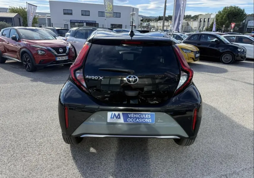 Vue arrière d'une Toyota Aygo X 2025 en vert aventurine avec toit noir, feux arrière en forme de boomerang.
