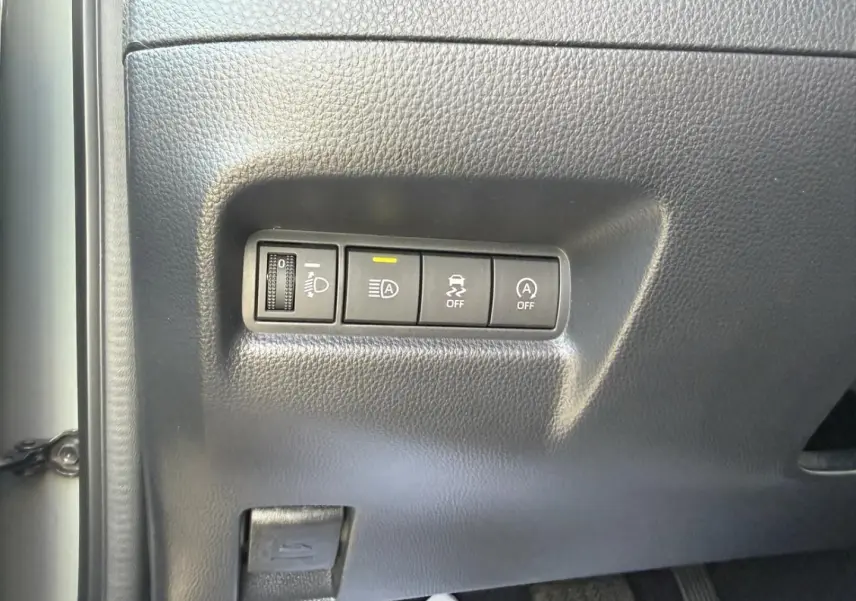 Gros plan sur les commandes de réglage des phares et d'assistance à la conduite dans une Toyota Aygo X 2025, intérieur noir.