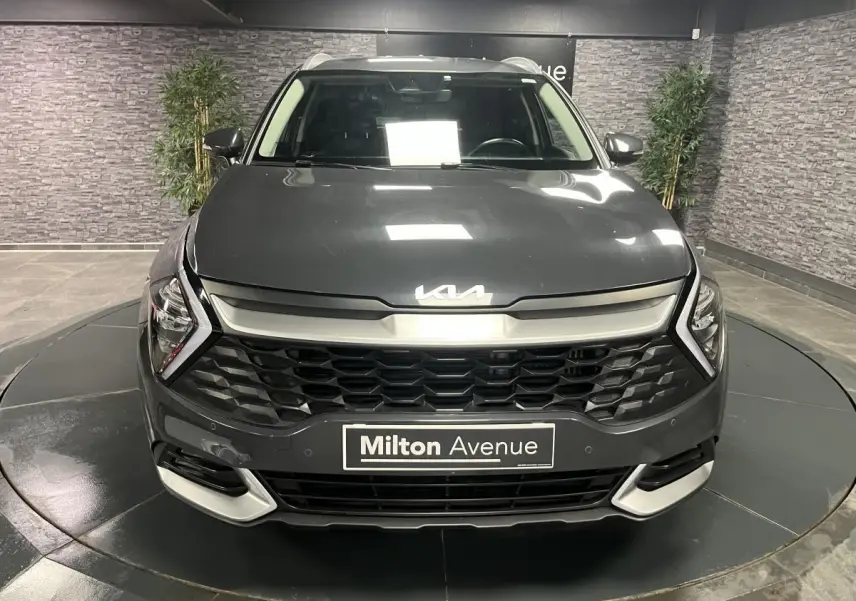 Vue frontale d'un KIA SPORTAGE gris métallisé 2022 avec calandre noire laquée et inserts chromés.