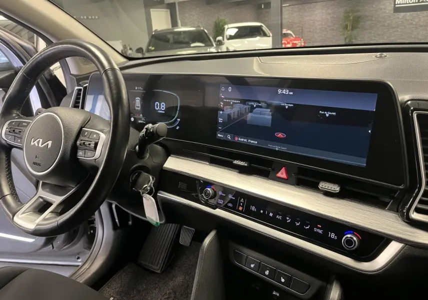 Vue intérieure du tableau de bord du Kia Sportage 2022 avec écran tactile large et volant cuir noir.