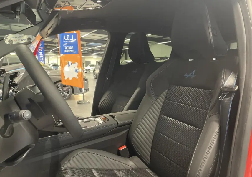 Intérieur côté conducteur du Renault Austral rouge, sièges sport Alcantara avec surpiqûres bleu blanc rouge et logo Alpine.