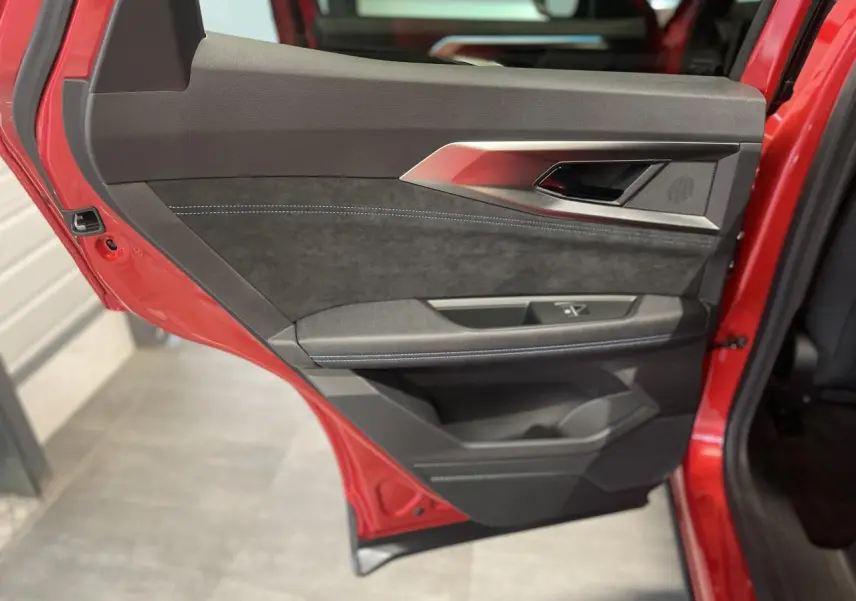 Vue rapprochée de la porte arrière gauche rouge métallisé du Renault Austral Esprit Alpine avec garniture noire et surpiqûres bleues.