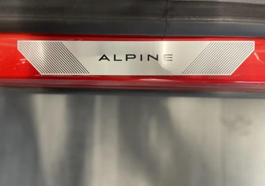 Plaque de seuil de porte ALPINE sur un Renault Austral rouge métallisé avec toit noir, vue en gros plan.