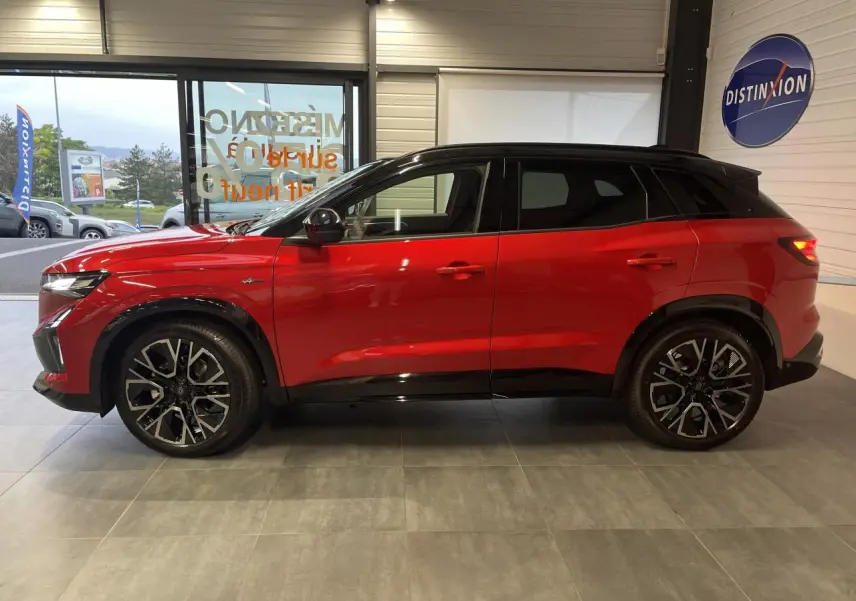 Profil côté gauche du Renault Austral rouge métallisé avec toit noir et jantes alliage 20 pouces en intérieur showroom.