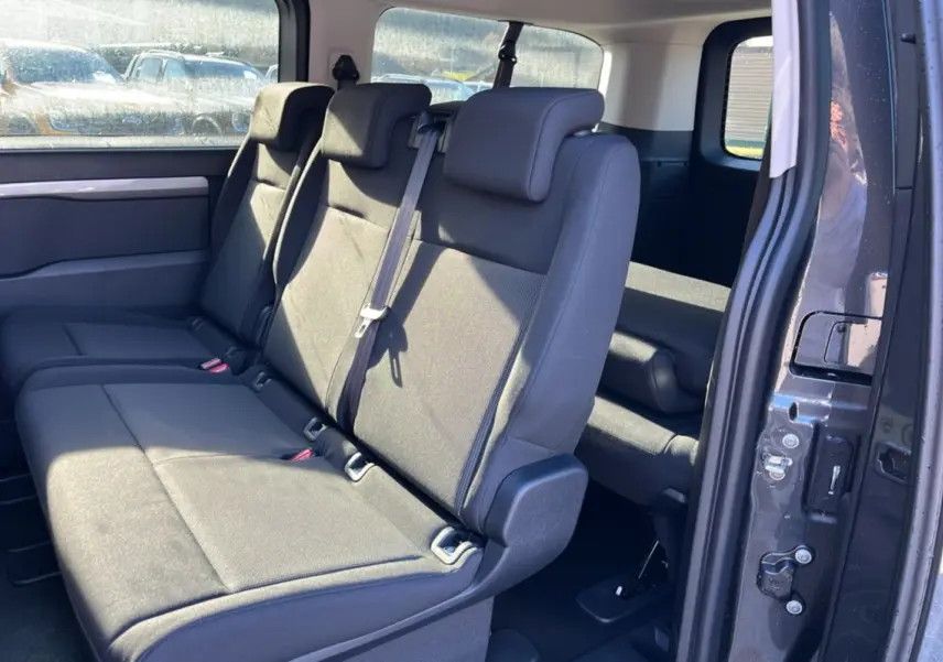Vue intérieure côté droit sur la banquette arrière grise du Peugeot Traveller 2.0 180 EAT8 XL Business avec porte coulissante ouverte.