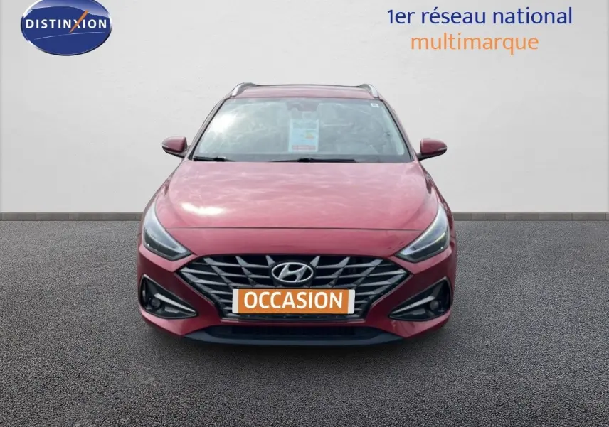 Vue avant d'une Hyundai i30 SW 2023 en rouge Sunset Red Metal avec calandre et phares LED distinctifs.