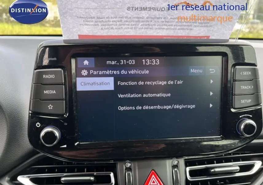Écran tactile central du tableau de bord de la Hyundai i30 SW 2023 en Sunset Red, affichant les paramètres de climatisation.