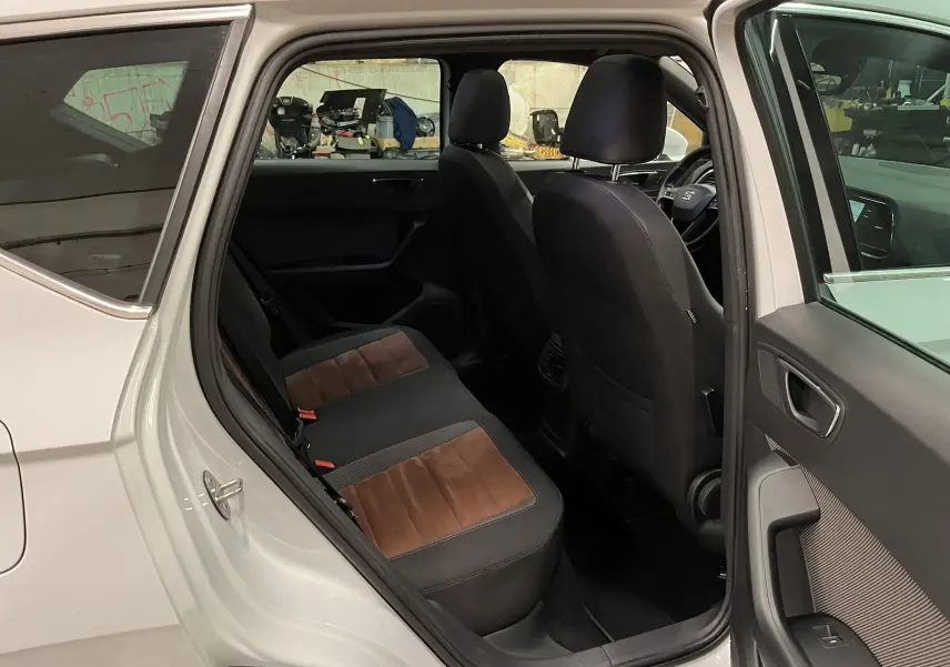 Vue intérieure côté gauche arrière du SEAT Ateca blanc, mettant en valeur les sièges bicolores en tissu et alcantara.