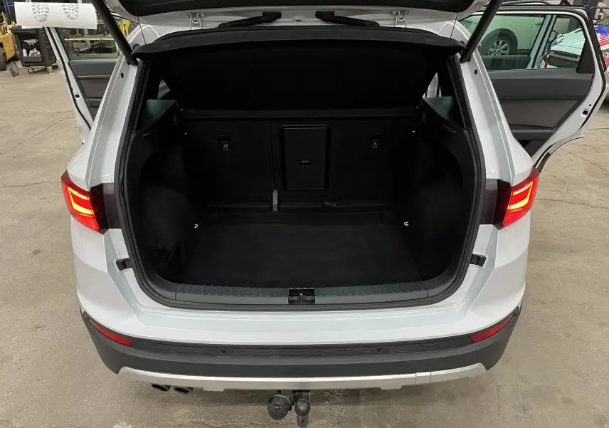Vue arrière du coffre ouvert d’un SEAT Ateca blanc 2016, avec portes arrière ouvertes et attelage visible.
