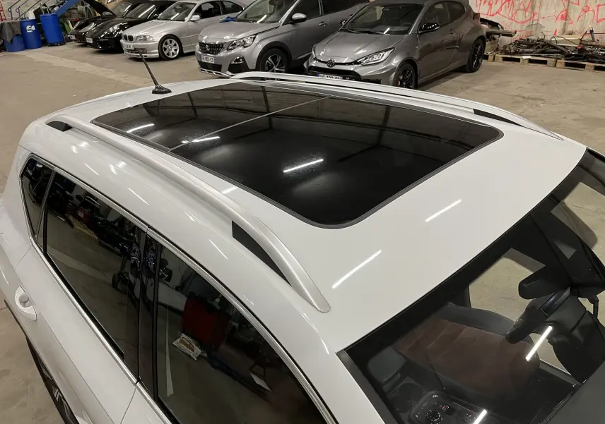Vue plongeante sur le toit panoramique et la partie gauche d’un SEAT Ateca blanc stationné en intérieur.