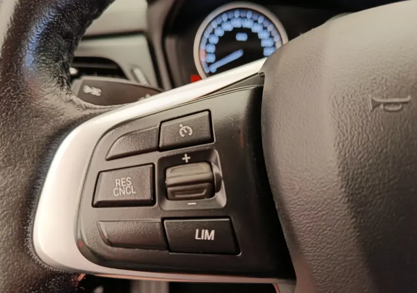 Gros plan sur le volant cuir et alu de la BMW Série 2 Gran Tourer gris clair, avec commandes multifonctions visibles.
