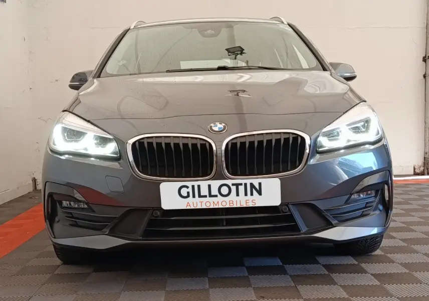 Vue frontale d'une BMW Série 2 Gran Tourer 218i Lounge gris clair avec phares LED allumés et calandre double haricot.