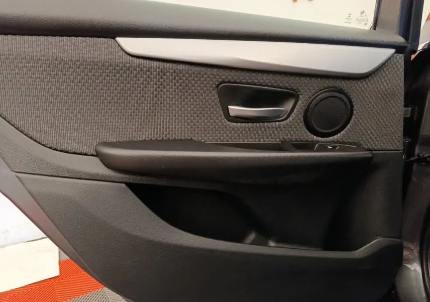 Vue rapprochée de la porte arrière droite intérieure grise de la BMW Série 2 Gran Tourer F46 avec poignée alu et haut-parleur rond.