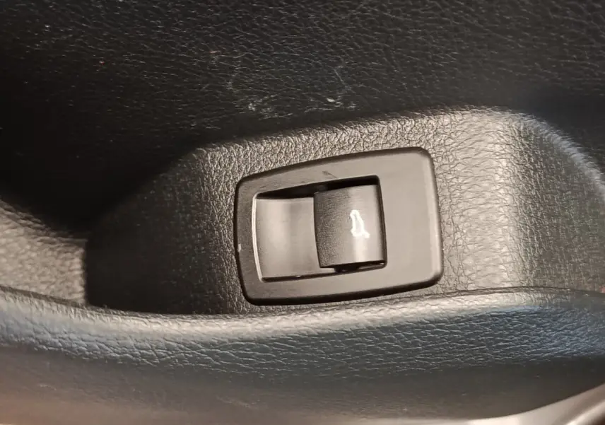 Gros plan sur le bouton d'ouverture électrique du coffre intérieur d'une BMW Série 2 Gran Tourer gris clair.