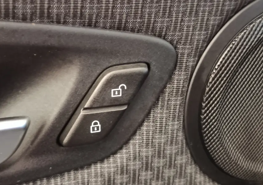 Gros plan sur les boutons de verrouillage centralisé sur la garniture de porte intérieure grise d'une BMW Série 2 Gran Tourer.