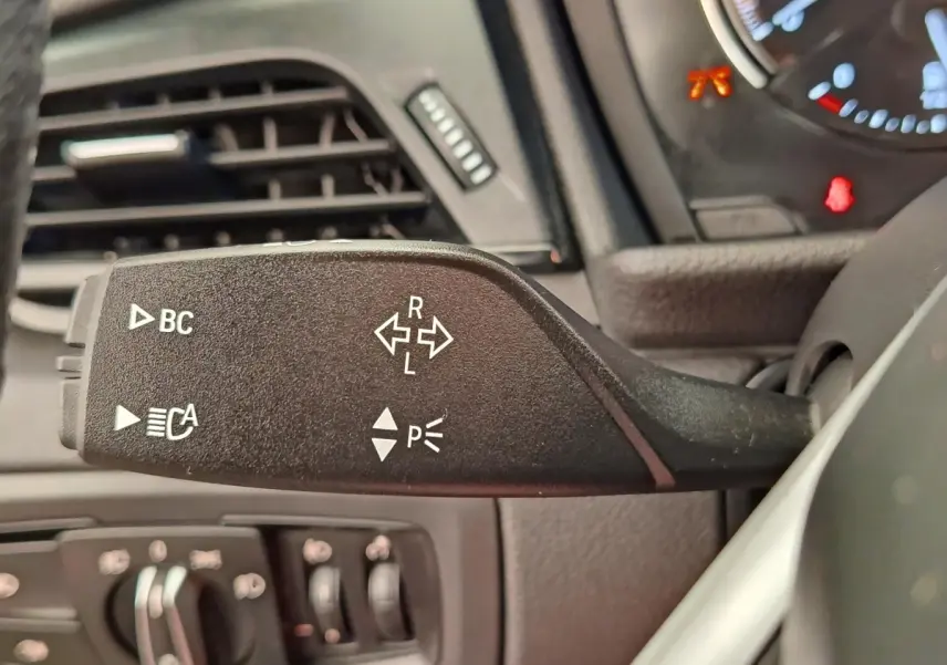 Gros plan sur la manette de clignotants noire du tableau de bord d’une BMW Série 2 Gran Tourer gris clair.