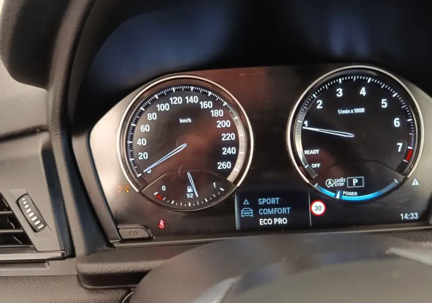 Gros plan sur le tableau de bord numérique de la BMW Série 2 Gran Tourer 218i, affichant modes de conduite et compte-tours.