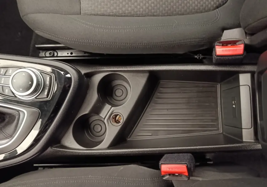 Vue plongeante sur la console centrale noire avec porte-gobelets et commande iDrive d'une BMW Série 2 Gran Tourer gris clair.