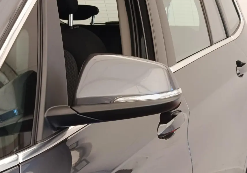 Gros plan sur le rétroviseur et la poignée côté conducteur d'une BMW Série 2 Gran Tourer gris clair.