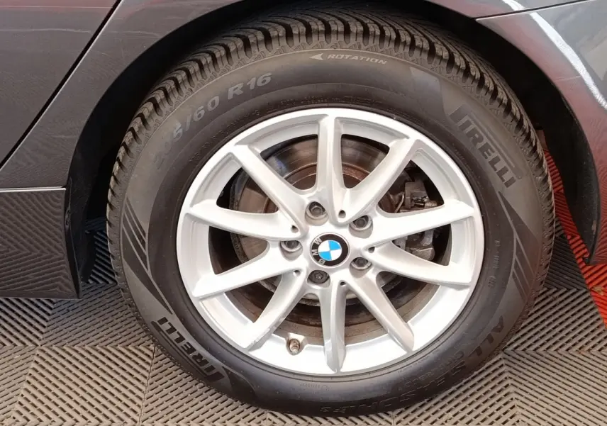 Gros plan sur la roue arrière droite d'une BMW Série 2 Gran Tourer 218i Lounge gris clair avec jante alliage 5 branches.