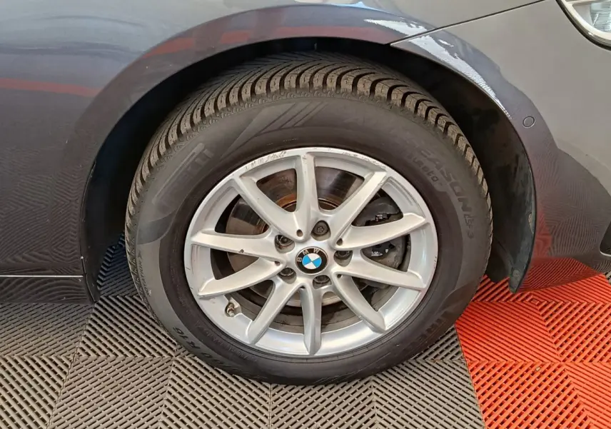Gros plan sur la roue avant droite gris clair d'une BMW Série 2 Gran Tourer F46 avec jante alu multi-branches.