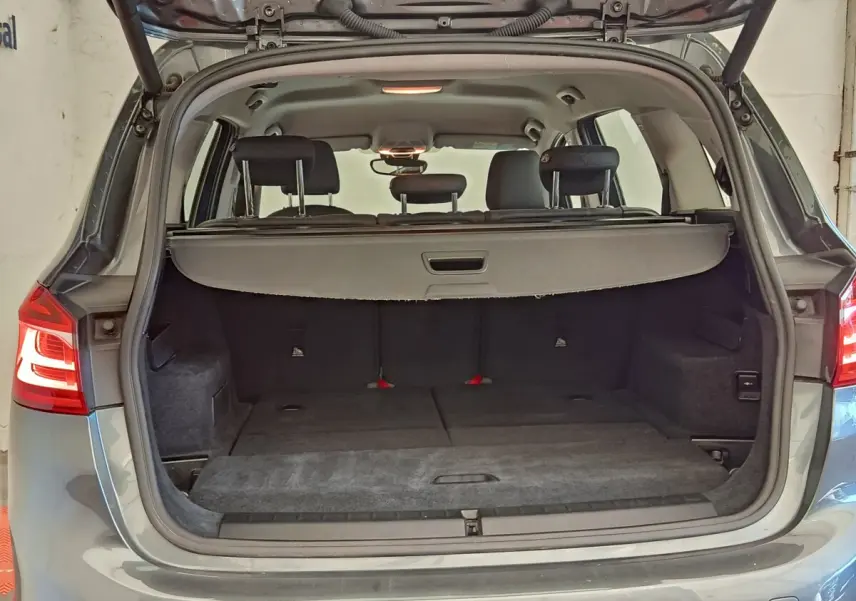 Coffre ouvert vu de l'arrière d'une BMW Série 2 Gran Tourer F46 gris clair, montrant les sièges rabattus et la tablette de coffre.